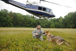 Staff Sgt. Jacob Twaddle, 11th Security Support Squadron military working dog handler, calms X, a military working dog, during a training mission in the National Capital Region, Aug. 19, 2015. X practiced jumping into and out of the UH-1N Twin Huey helicopter and staying calm while in close proximity to the helicopter. (U.S. Air Force Photo/ Airman 1st Class J.D. Maidens)