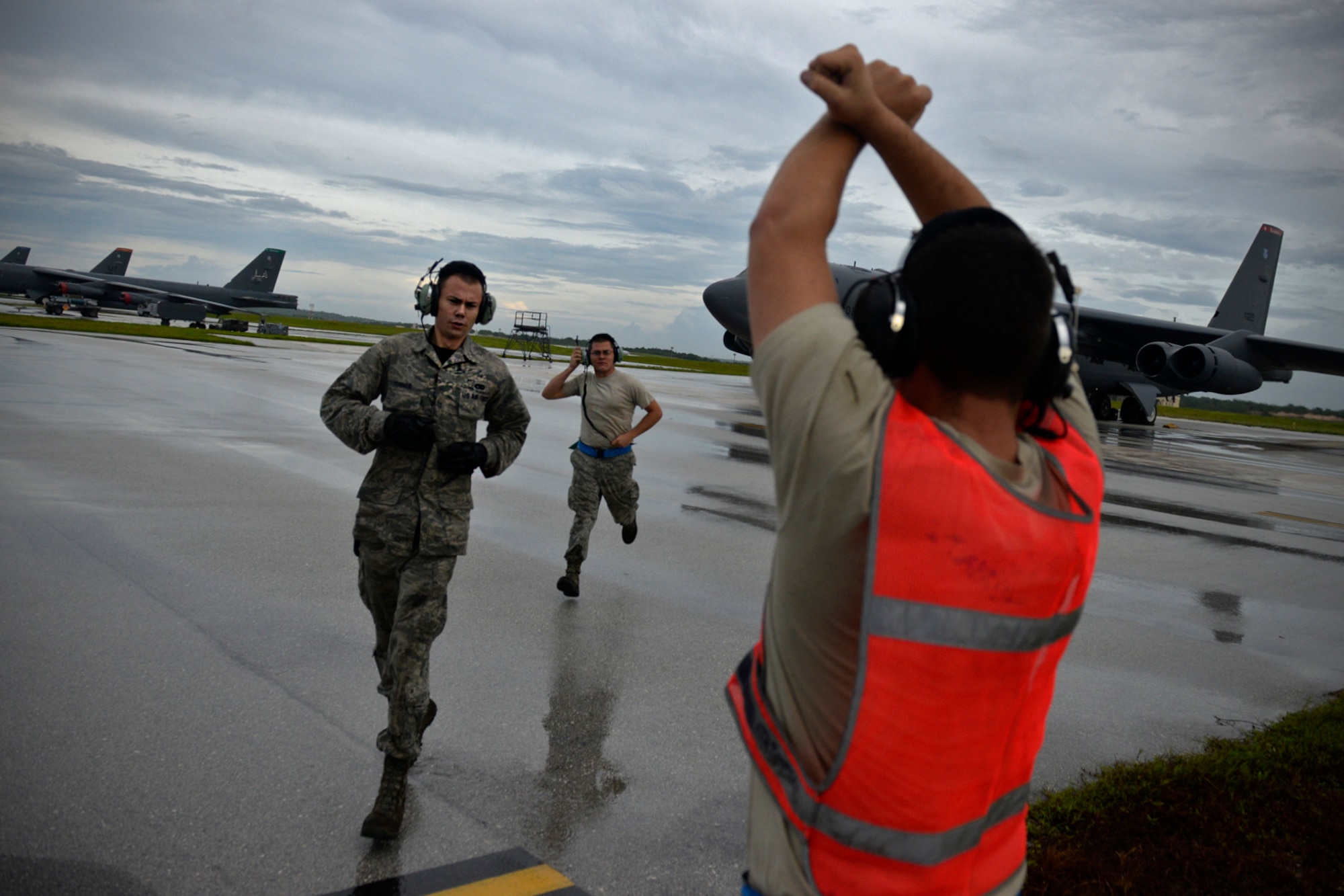 Senior Airman Taylor Giordano, right, signals to the pilot on a B-52 Stratofortress, as his wingmen Senior Airman Logan Turner, left, and Staff Sgt. Stephen Cole get into position to launch their aircraft Aug. 22, 2015, at Andersen Air Force Base, Guam. The Airmen are B-52 crew chiefs assigned to the 20th Expeditionary Aircraft Maintenance Squadron. Bomber crews with the 20th Expeditionary Bomb Squadron are part of U.S. Pacific Command’s continuous bomber presence and support ongoing  operations in the Indo-Asia-Pacific region. (U.S. Air Force photo by Staff Sgt. Alexander W. Riedel/Released)