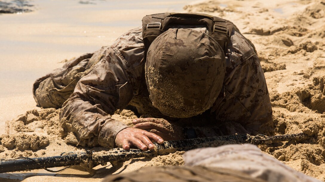 Sgt. Jason Hunter, the training noncommissioned officer in charge of Headquarters Company, 3rd Marine Regiment and a Murrieta, Calif., native, keeps his head low as he low crawls along Fort Hase Beach aboard Marine Corps Base Hawaii during Sergeants Course, Aug. 19, 2015. Hunter, along with the other sergeants in the course, were low crawling in a tricky scenario where they were outnumbered four to one, and needed to repair a broken down vehicle. Sergeants Course is a vital part of professional military education for any Marine and helps to maintain the standards amongst the NCOs of the Marine Corps. The course supports MCB Hawaii’s mission, which is to provide facilities, programs and services in direct support of units, individuals and families to enhance and sustain combat readiness for all operating forces and tenant organizations aboard the installation.
