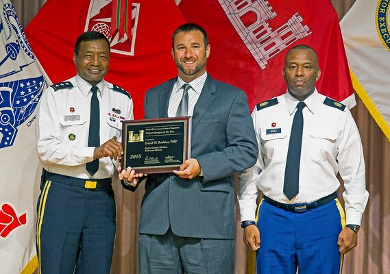 Lt. Gen. Thomas P. Bostick, U.S. Army, chief of engineers, presents Dave Robbins, Baltimore District geographer and study manager, with the 2015 Project Manager of the Year award at the U.S. Army Corps of Engineers National Awards Ceremony, held at the Government Accountability Office in Washington, D.C., Aug. 6, 2015. Command Sgt. Maj. Antonio S. Jones, U.S. Army Corps of Engineers (right), is also pictured. (U.S. Army Photo by Jhi Scott)