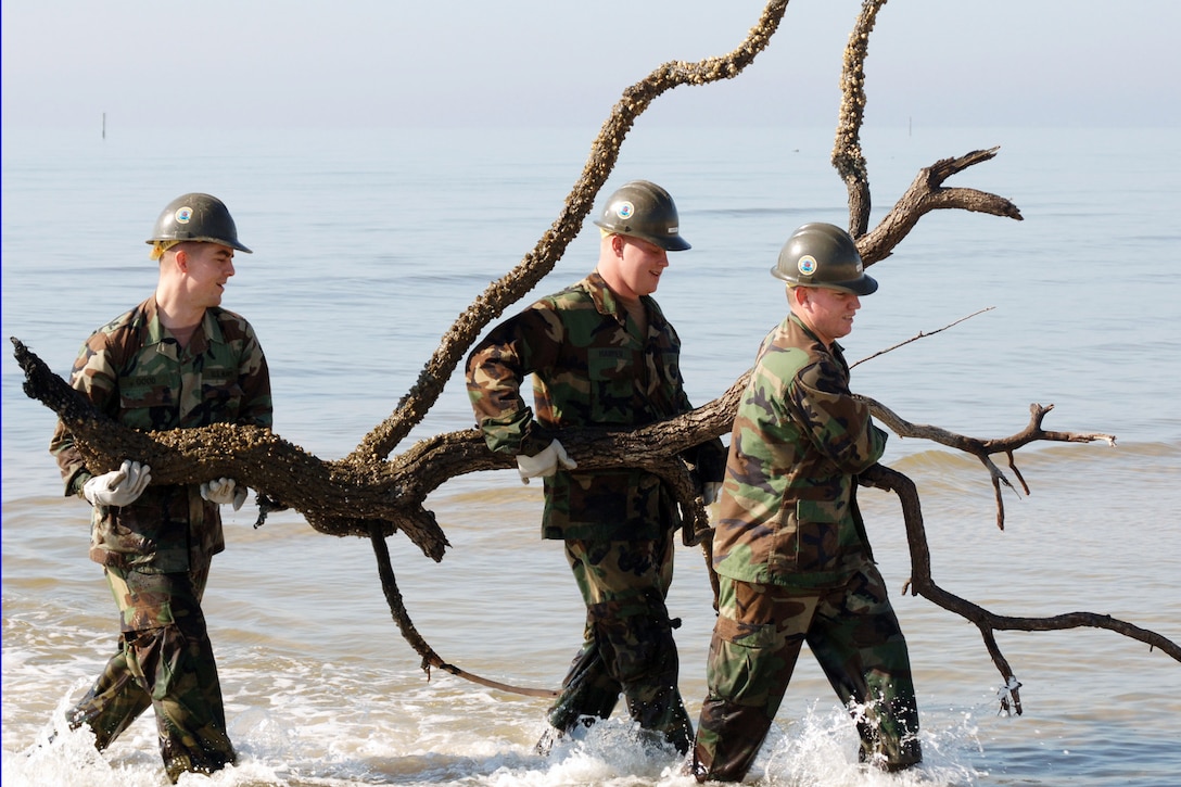 Navy personnel remove debris from ankle-deep water off the coast of Mississippi during the Great American Cleanup event in Biloxi, Miss., March 2, 2006.  Naval Mobile Construction Battalion-74 joined volunteers from the surrounding community and across the nation in a continuing effort to clean up and rebuild the Gulf Coast region following Hurricane Katrina in 2005. U.S. Navy photo by Petty Officer 1st Class Rob Wesselman 

