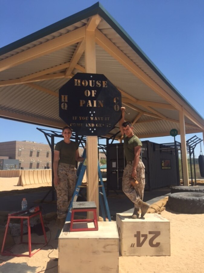 Pfc. Olivia A. Ornouski (C Company) and Lance Cpl. Juan J. Ayala (HQ Company) assist in mounting the new “House of Pain” sign at the MCCES Tactical Facility. The sign was handmade by Marines of HQ Company MCCES.