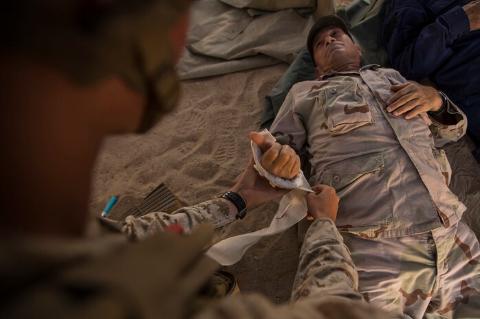 U.S. Navy Seaman Apprentice Isaac Montalvo, hospitalman with Company A, 1st Battalion, 7th Marine Regiment, renders medical aid to a simulated casualty during security force operations as a part of Large Scale Exercise (LSE) at Marine Corps Air Ground Combat Center Twentynine Palms, Calif., Aug. 18, 2015. LSE is a joint forces exercise conducted at the brigade level designed to enable live, virtual, and constructive training for participating units and allows participating nations to strengthen partnerships and their ability to operate together. (U.S. Marine Corps photo by Lance Cpl. Clarence A. Leake/Released)