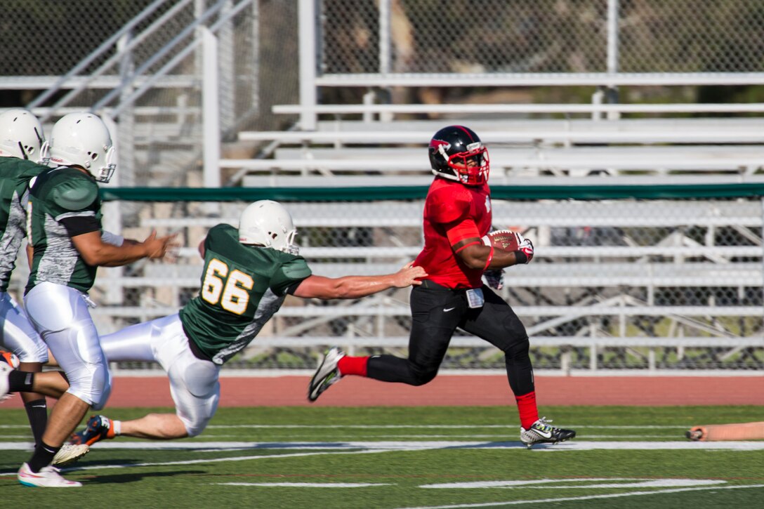 Cpl. Kyle Byrdsong, a running back for the Marine Corps Air Station Miramar Falcons, avoids a tackle while running the ball during a football game against the 1st Maintenance Battalion War Machines aboard Marine Corps Base Camp Pendleton, California, Aug. 24. The Miramar Falcons won the game with a score of 35-0. (U.S. Marine Corps photo by Cpl. Alissa P. Schuning/Released)