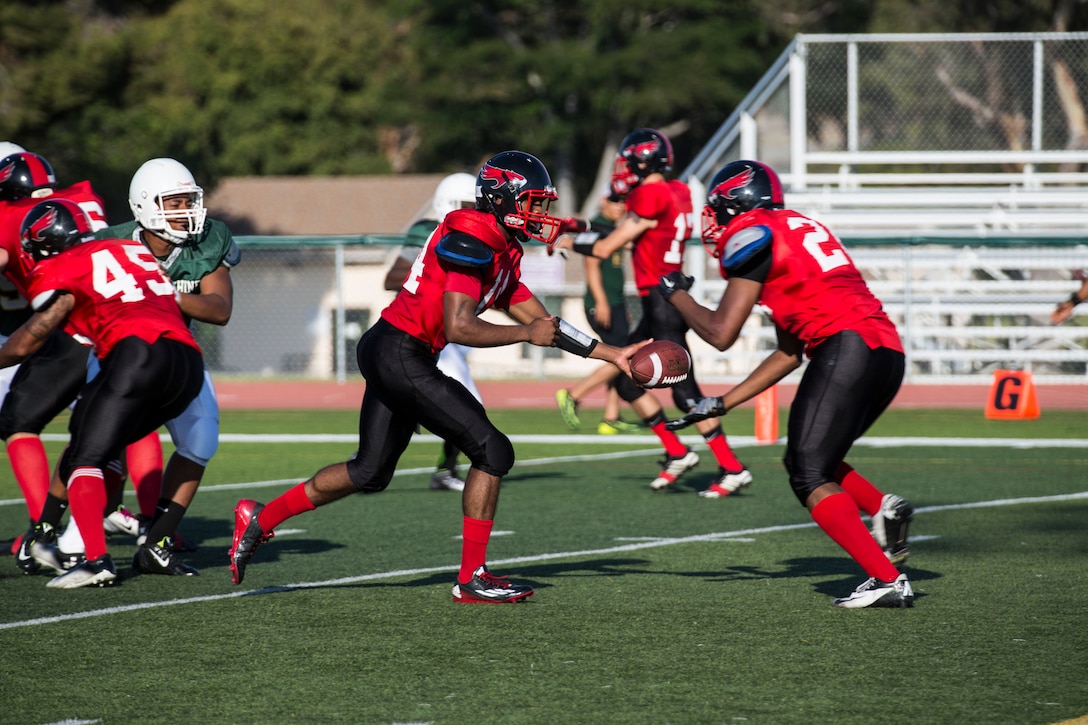 Lance Cpl. Reginald Cooper, a quarterback for the Marine Corps Air Station Miramar Falcons, hands the ball off to Cpl. Eric Campbell, a wide receiver for the Miramar Falcons, during a football game against the 1st Maintenance Battalion War Machines aboard Marine Corps Base Camp Pendleton, California, Aug. 24. The Miramar Falcons won the game with a score of 35-0. (U.S. Marine Corps photo by Cpl. Alissa P. Schuning/Released) 