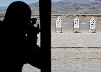 A participant in the M4 rifle qualification course fires his M4 at the 99th Security Forces Squadron Combat Arms Training and Maintenance firing range on Nellis Air Force Base, Nev., Aug. 18, 2015. Airmen aimed at six targets with three on each side designated for either iron sights or red dot sights to qualify on the M4 rifle. (U.S. Air Force photo by Airman 1st Class Jake Carter)