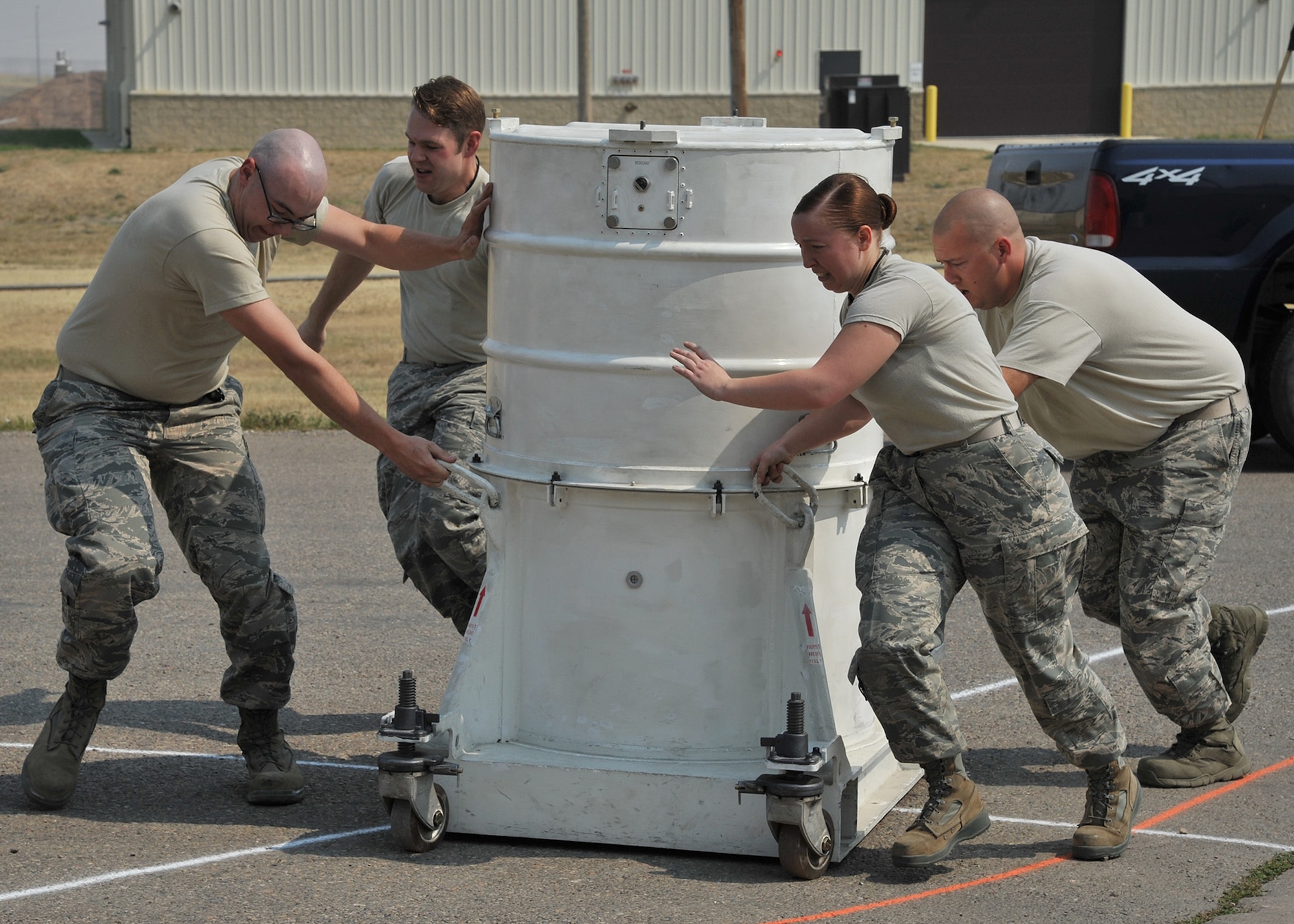 Senior Airman Matthew Gish, Staff Sgt. Aaron Hayworth, Senior Airman Megan Dees, and Tech. Sgt. Robert DeMarino, all from the 341st Munitions Squadron, scramble to move an empty warhead storage container through a serpentine course Aug. 25, 2015, at the Malmstrom Air Force Base, Mont., weapons storage area. Malmstrom’s Global Strike Challenge 2015 MUNS team was practicing for a ‘handling rodeo,’ a timed event in Air Force Global Strike Command’s ICBM maintenance competition and one of three events that the 341st Missile Wing’s GSC 2015 MUNS team will compete in Sept. 2-4. The results will be revealed in October and compared to similar teams from Minot AFB, N.D., and F.E. Warren AFB, Wyo. (U.S. Air Force photo/John Turner)