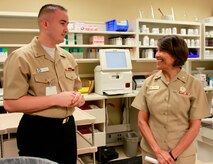 Hospitalman Dalton Terrell, pharmacy technician, Naval Health Clinic Charleston, describes the daily operations of and services provided at NHCC's pharmacy, for Rear Adm. Raquel Bono, chief, Navy Medical Corps and director, National Capital Region Medical Directorate , Aug. 21, 2015 during Bono's visit to NHCC. Bono also met with NHCC command leadership, visited various departments throughout the clinic, and spoke with staff members about the future of Navy medicine and what's on the horizon for military health care through the collaboration of joint service operations. (Navy photo/ Hospitalman Mark Simon)