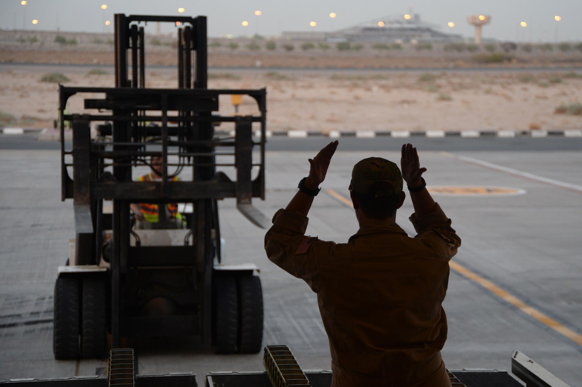 U.S. Air Force Senior Airman Rebecca, 816th Expeditionary Airlift Squadron loadmaster, guides a pay-loader to unload cargo on board a C-17 Globemaster III in support of Operation Inherent Resolve in Kuwait, August 14, 2015. OIR is the military intervention against Daesh. (U.S. Air Force photo by Staff Sgt. Sandra Welch) 