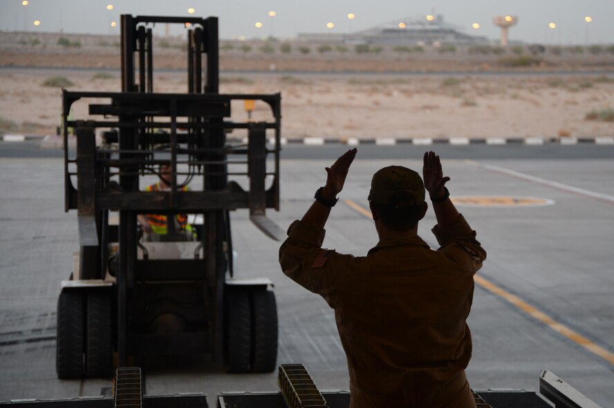 U.S. Air Force Senior Airman Rebecca, 816th Expeditionary Airlift Squadron loadmaster, guides a pay-loader to unload cargo on board a C-17 Globemaster III in support of Operation Inherent Resolve in Kuwait, August 14, 2015. OIR is the military intervention against Daesh. (U.S. Air Force photo by Staff Sgt. Sandra Welch) 