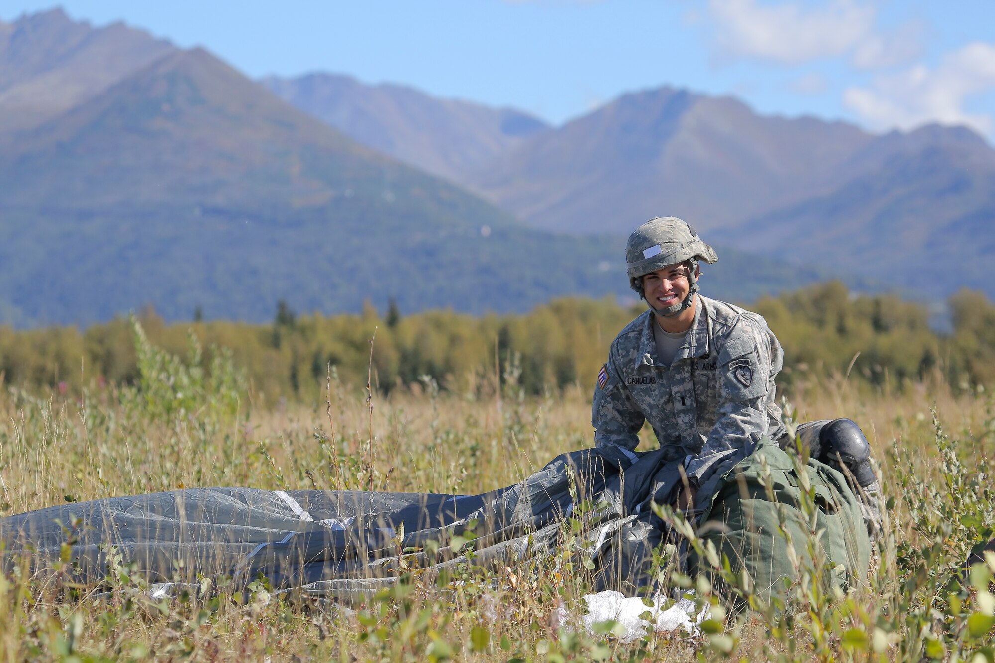 U.S. Army 1st Lt. Kristopher Candelaria, a native of Fayetteville, N.C., assigned to 1st Battalion (Airborne), 501st Infantry Regiment, 4th Infantry Brigade Combat Team (Airborne), 25th Infantry Division, recovers his parachute after conducting a practice jump over Malemute drop zone, Joint Base Elmendorf-Richardson, Alaska, Aug. 24, 2015. Japanese Ground Self-Defense Force and U.S. Army paratroopers conducted the practice jump utilizing Royal Australian and U.S. Air Force aircraft as part of Pacific Airlift Rally 2015, a biennial, multilateral tactical military symposium designed to enhance military airlift interoperability and cooperation between nations of the Pacific region for future humanitarian missions. (U.S. Air Force photo/Alejandro Pena)