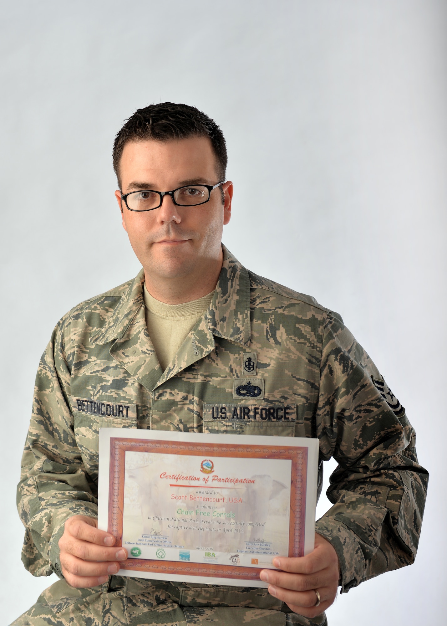 U.S. Air Force Tech. Sgt. Scott Bettencourt, a pharmacy flight chief with the 55th Medical Support Squadron, poses with a certificate he received from Jamal Jung Kunwar, chief conservation of Chitwan National Park, Nepal, after spending two weeks building an elephant corral on Aug. 26, Offutt Air Force Base, Neb.  The corrals are replacing the chains used by elephant handlers to keep their working elephants in place.  Corrals have been proven to improve the health and demeanor of the elephants and are being widely adopted by working elephant handlers throughout the world.  (U.S. Air Force photo by Josh Plueger/Released)