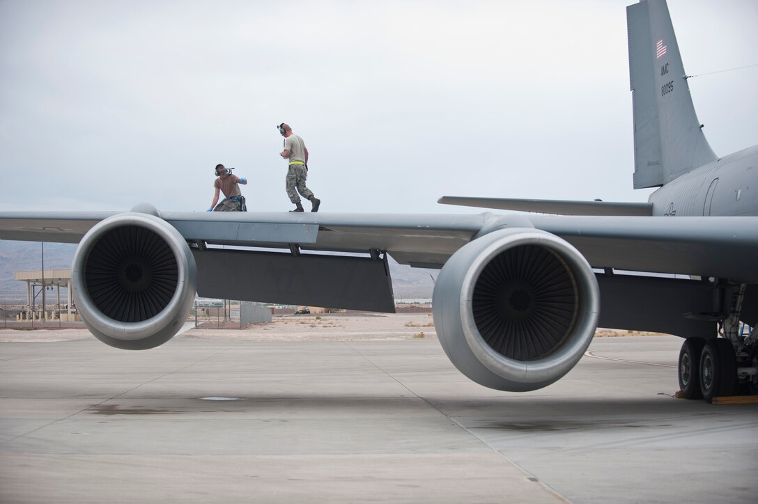 Staff Sgt. David Atteberry, left, an aircraft hydraulic systems technician assigned to the 92nd Aircraft Maintenance Squadron, Fairchild Air Force Base, Wash., signals to a fellow maintainer while working on the wing of a KC-135 Stratotanker during Red Flag 15-4 at Nellis AFB, Nev., Aug. 25, 2015. Red Flag provides realistic combat training in a contested, degraded and operationally-limited environment, which provides aircrews with real-time war scenarios and helps ground crews test and improve their operational readiness. (U.S. Air Force photo by Staff Sgt. Siuta B. Ika)