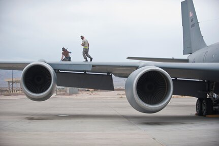 Staff Sgt. David Atteberry, left, an aircraft hydraulic systems technician assigned to the 92nd Aircraft Maintenance Squadron, Fairchild Air Force Base, Wash., signals to a fellow maintainer while working on the wing of a KC-135 Stratotanker during Red Flag 15-4 at Nellis AFB, Nev., Aug. 25, 2015. Red Flag provides realistic combat training in a contested, degraded and operationally-limited environment, which provides aircrews with real-time war scenarios and helps ground crews test and improve their operational readiness. (U.S. Air Force photo by Staff Sgt. Siuta B. Ika)