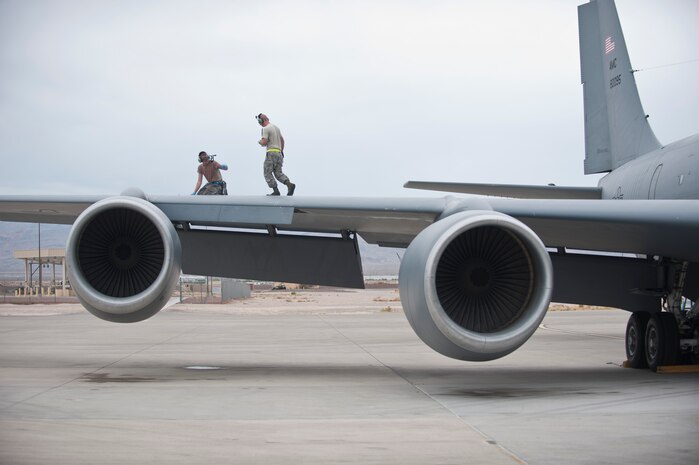 Staff Sgt. David Atteberry, left, an aircraft hydraulic systems technician assigned to the 92nd Aircraft Maintenance Squadron, Fairchild Air Force Base, Wash., signals to a fellow maintainer while working on the wing of a KC-135 Stratotanker during Red Flag 15-4 at Nellis AFB, Nev., Aug. 25, 2015. Red Flag provides realistic combat training in a contested, degraded and operationally-limited environment, which provides aircrews with real-time war scenarios and helps ground crews test and improve their operational readiness. (U.S. Air Force photo by Staff Sgt. Siuta B. Ika)