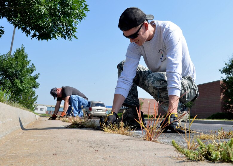 Staff Sgt. Gordon Burton (front) and Master Sgt. Ryan Laube, both from the 50th Contracting Squadron, pull weeds in the Ellicott Elementary School parking lot in Ellicott, Colorado, during a cleanup event Friday, Aug. 21, 2015. There are many volunteer opportunities available in the Ellicott School District, those who would like to volunteer should contact Master Sgt. David Wright, Top III liaison for Ellicott School, at 719-567-3811 or contact the Ellicott School District Office at 719-683-2700. (U.S. Air Force photo/Staff Sgt. Debbie Lockhart)