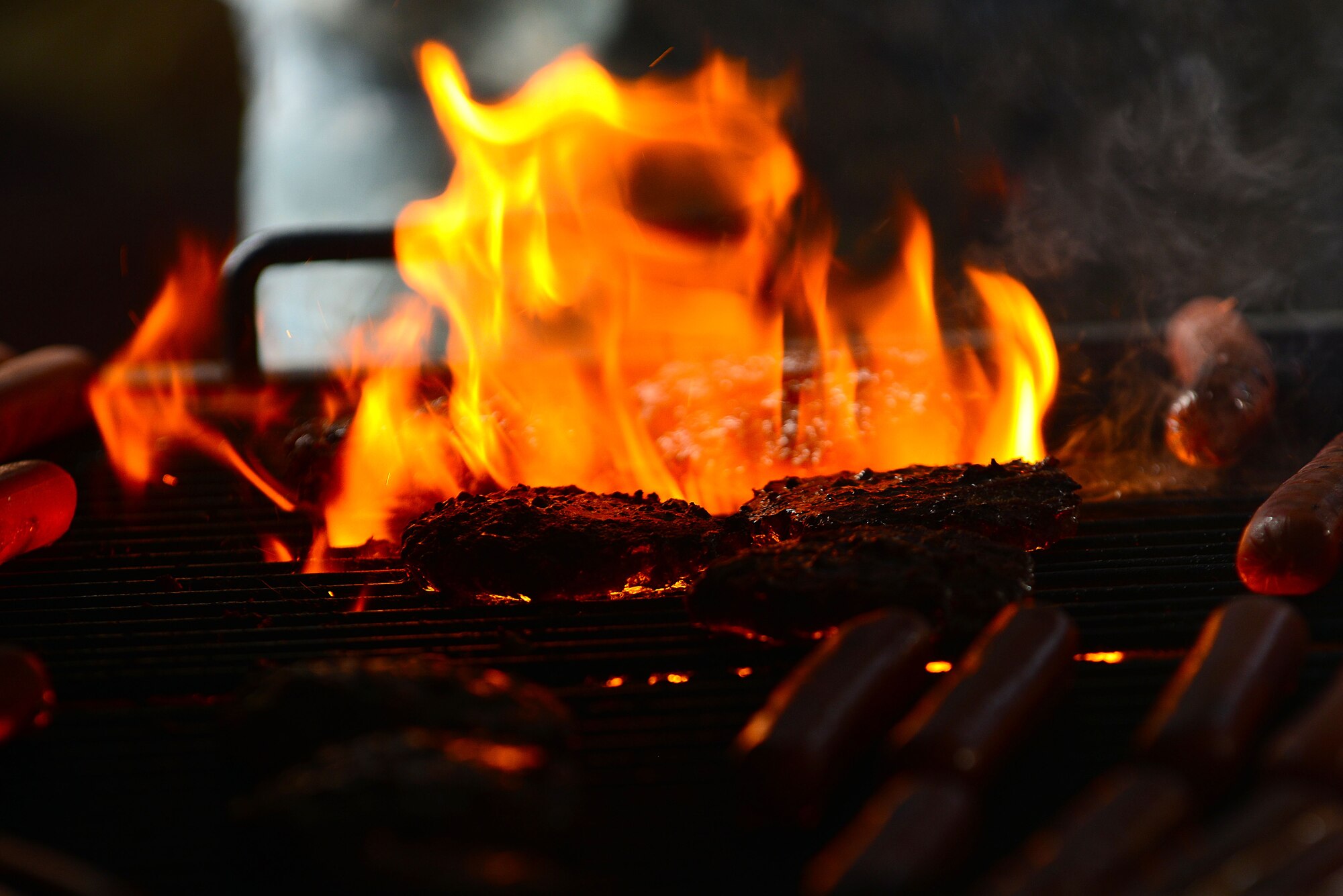 Burgers and hotdogs cook on a grill during a First Term Airmen Center mentorship lunch at Langley Air Force Base, Va., Aug. 21, 2015. The FTAC staff teamed up with members of the Langley Club 5/6 in an attempt to bridge the gap between new Airmen and noncommissioned officers through a face-to-face mentorship event. (U.S. Air Force photo by Senior Airman Kimberly Nagle/Released)