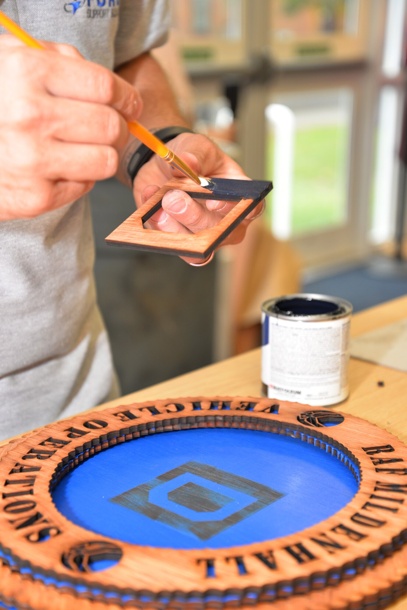 Stephen Fournier, 100th Force Support Squadron Arts and Crafts staff member from Richlands, N.C., paints wood used to form the background of the “Square D” on a 3-D wood plaque for a customer Aug. 20, 2015, on RAF Mildenhall, England. Using a laser machine, Fournier is able to transform wood into unique leaving gifts, awards or personal gifts. (U.S. Air Force photo by Karen Abeyasekere/Released)