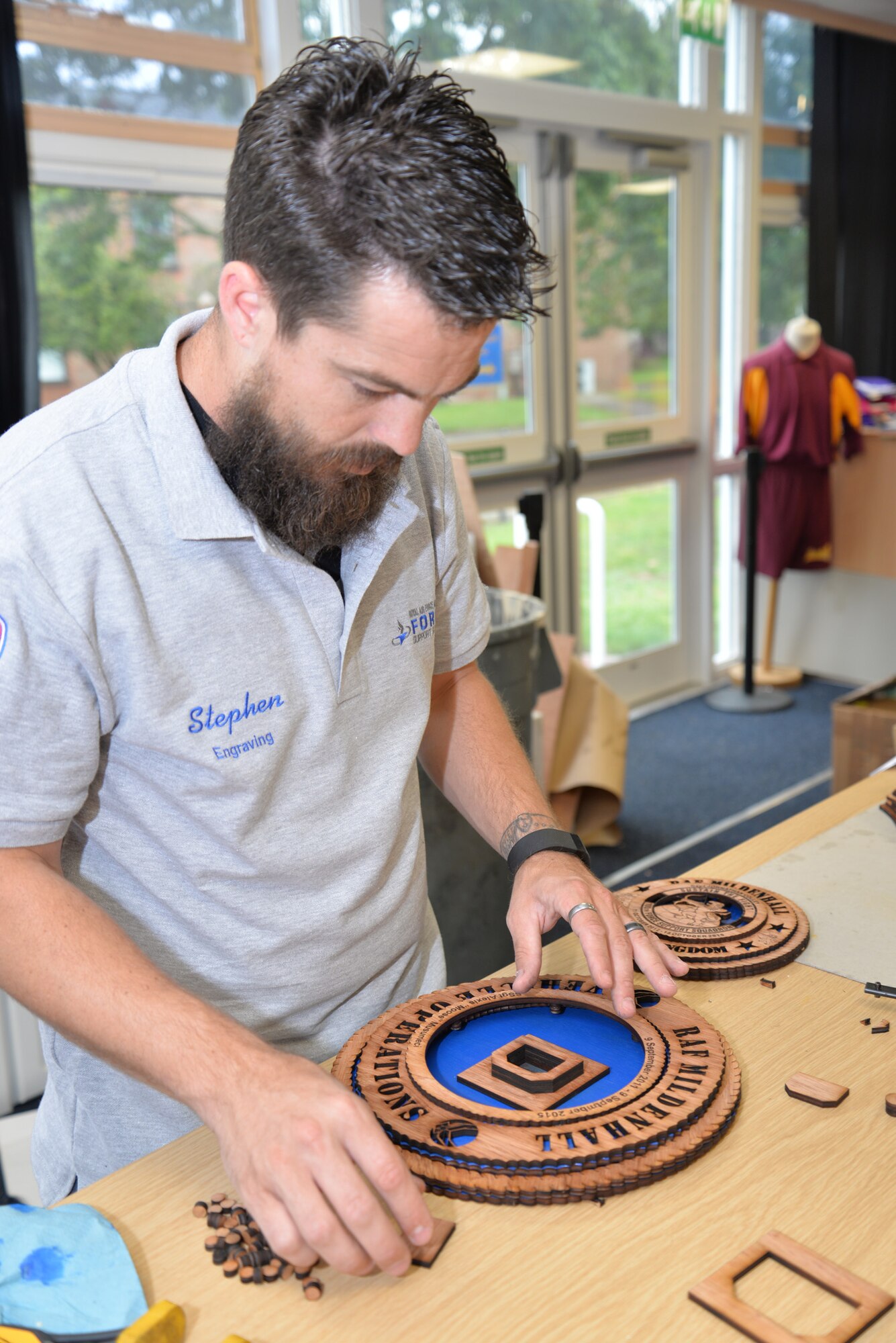 Stephen Fournier, 100th Force Support Squadron Arts and Crafts staff member from Richlands, N.C., creates a custom-designed 3-D wood plaque for a customer Aug. 20, 2015, on RAF Mildenhall, England. The arts and crafts shop offers a variety of services including framing, embroidery, engraving and laser-engraved products made from wood. The 100th FSS facility can engrave onto items made of materials such as glass, wood and slate, and create unique items for leaving gifts or awards. (U.S. Air Force photo by Karen Abeyasekere/Released)