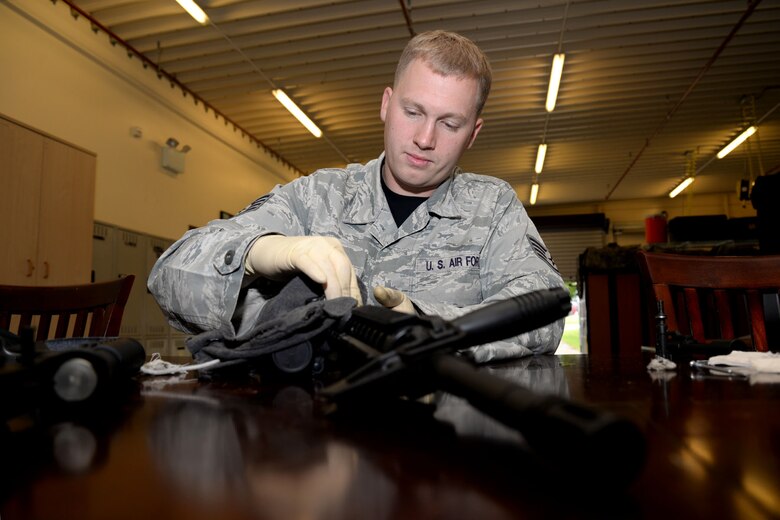 U.S. Air Force Staff Sgt. Daniel Henderson, 352nd Special Operations Support Squadron Deployed Aircraft Ground Response Element team member from Richfield, Utah, cleans a rifle during routine maintenance Aug. 21, 2015, on RAF Mildenhall, England. Henderson was selected for the Square D Spotlight for portraying the core value of Excellence in All We Do. (U.S. Air Force photo by Senior Airman Kate Thornton/Released)