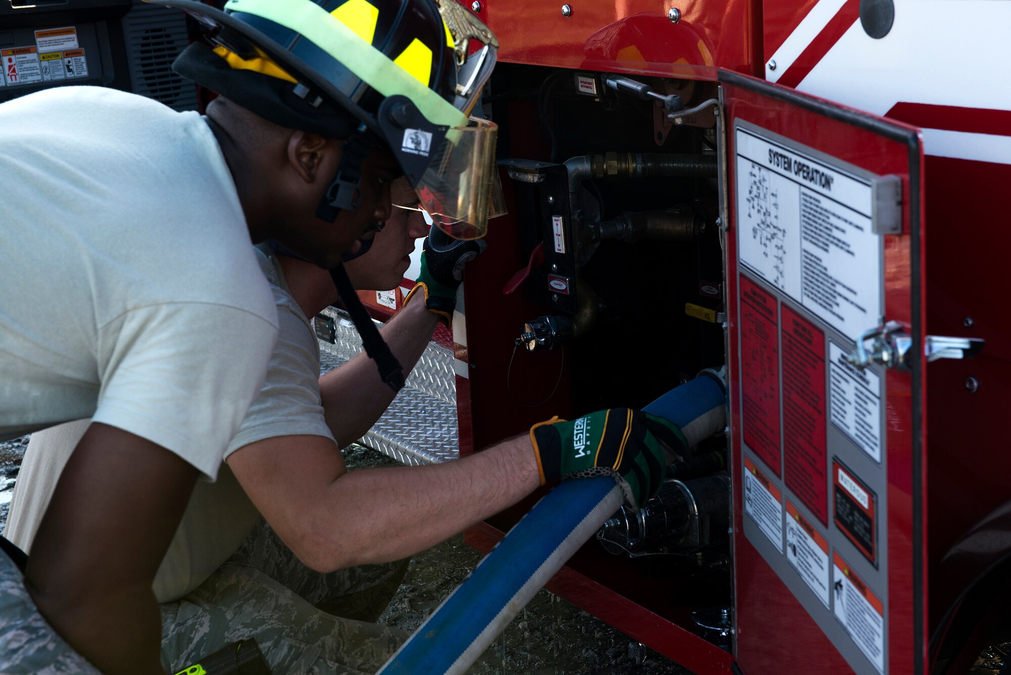 U.S. Air Force Airman 1st Class Jeffrey Young (left) and Senior Airman Cody Jones, 23d Civil Engineer Squadron fire team members, connect a hose to a stryker fire truck Aug. 20, 2015, at Moody Air Force Base, Ga. They filled up the 1,500-gallon tank as quickly as possible to ensure the aircraft was always being hosed down. (U.S. Air Force photo by Airman 1st Class Kathleen D. Bryant/Released)

