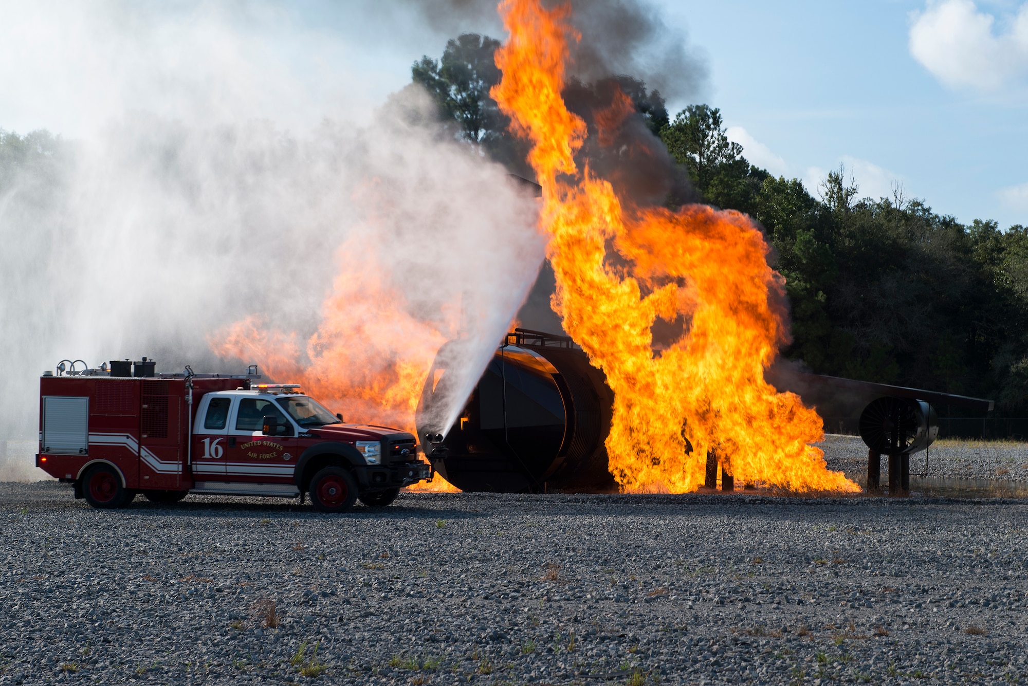 A 23d Civil Engineer Squadron rapid intervention vehicle sprays water on a simulated aircraft fire during a live-fire burn exercise Aug. 20, 2015, at Moody Air Force Base, Ga. The fire department holds this training quarterly to keep fire team members proficient in aircraft incidents. (U.S. Air Force photo by Airman 1st Class Kathleen D. Bryant/Released)
