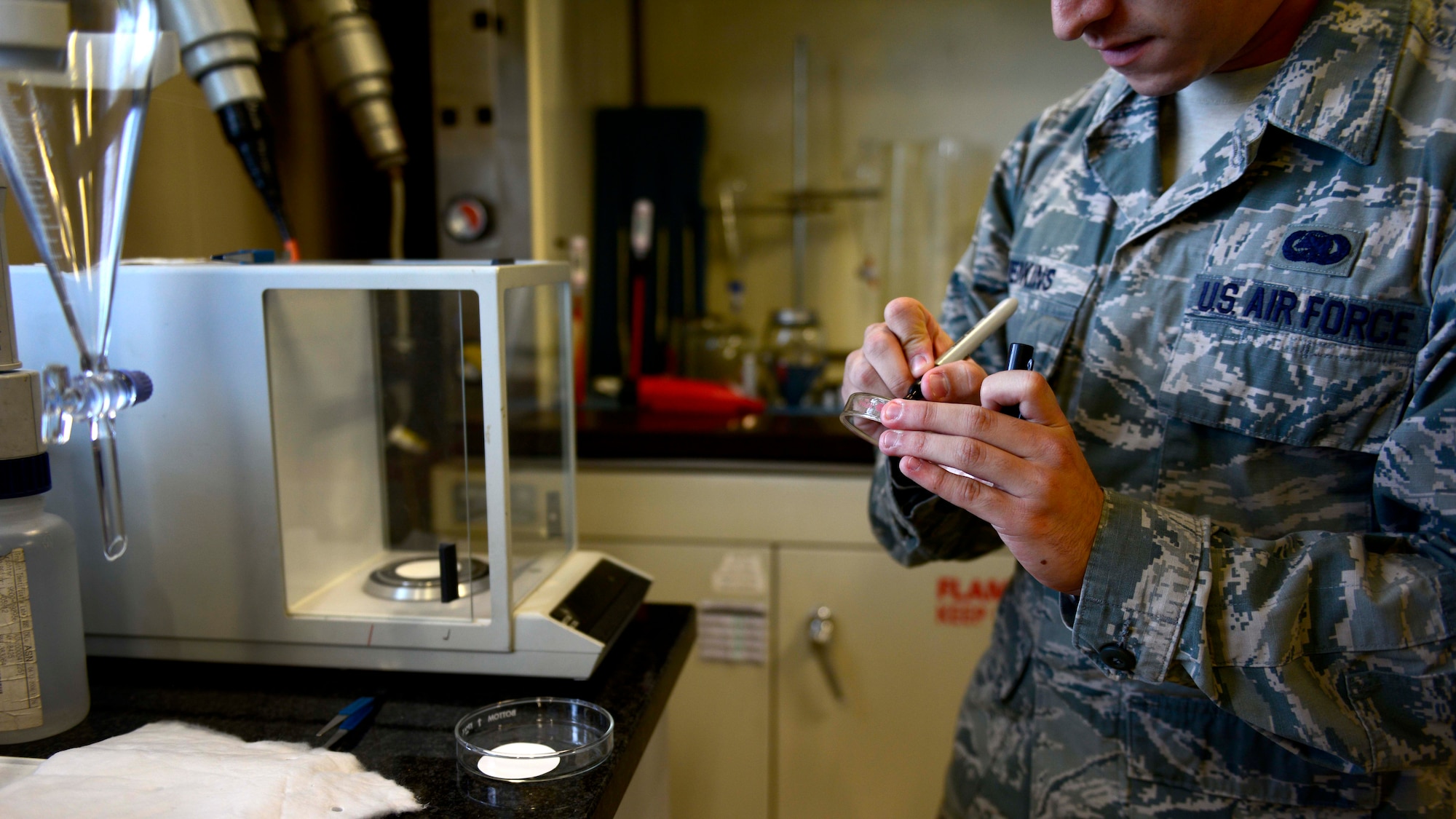 U.S. Air Force Senior Airman Adrian Jenkins, 31st Logistics Readiness Squadron petroleum oils and lubricants lab technician, documents the weight of filtration pads, Aug. 25, 2015, at Aviano Air Base, Italy. Filtration pads are used by POL Airmen to determine how many particles are in the fuel. (U.S. Air Force photo by Senior Airman Areca T. Wilson/Released)