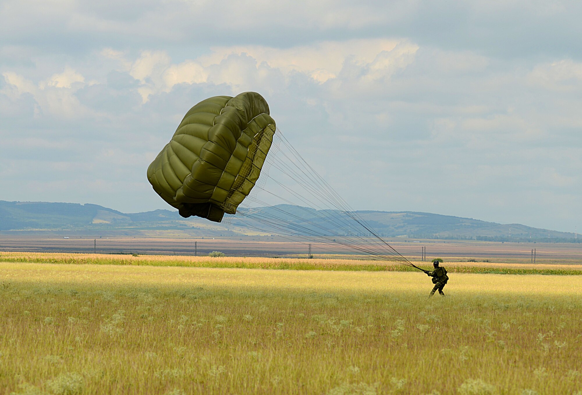 A Romanian paratrooper recovers his parachute after jumping from a U.S. Air Force C-130J Super Hercules Aug. 18, 2015, at Boboc Air Base, Romania. For two weeks, U.S. and Romanian forces trained alongside each other to get a better working knowledge of each other conduct airborne operations. (U.S. Air Force photo/Senior Airman Timothy Moore)