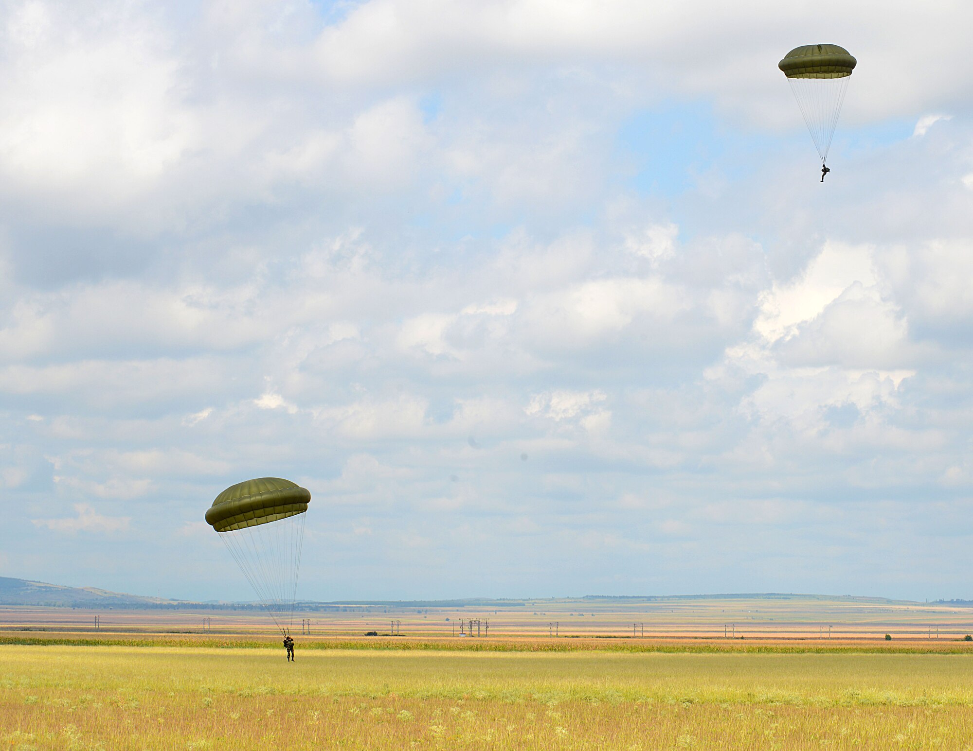 Romanian paratroopers land on the drop zone after jumping from a U.S. Air Force C-130J Super Hercules Aug. 18, 2015, at Boboc Air Base, Romania. Approximately 60 Romanian paratroopers performed airborne operations via the three U.S. Air Force C-130Js participating during the first week of the two-week long exercise Carpathian Summer. (U.S. Air Force photo/Senior Airman Timothy Moore)