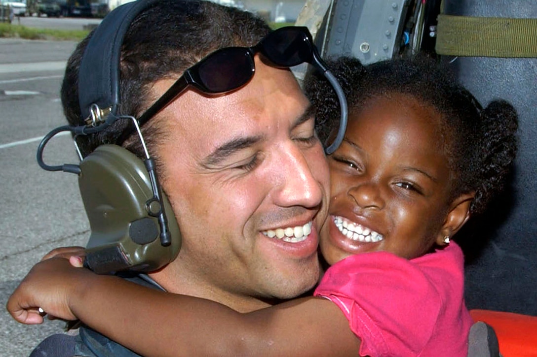 A young Hurricane Katrina survivor hugs her rescuer, Air Force Staff Sgt. Mike Maroney, after she was relocated to the New Orleans International Airport in New Orleans, Sept. 7, 2005. Maroney is a pararescueman assigned to the 58th Rescue Squadron on Nellis Air Force Base. The Air Force Special Operations Command and various Guard rescue squadrons worked together to aid in rescue efforts of Hurricane Katrina victims. U.S. Air Force P\photo by Airman 1st Class Veronica Pierce