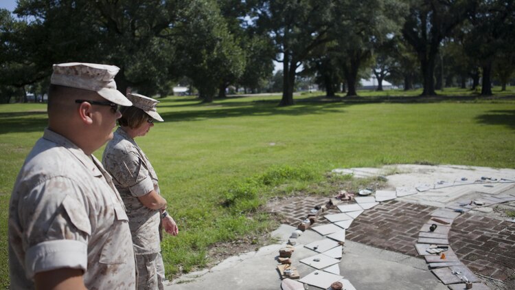 CWO4 Jerod Murphy, assistant ordnance officer for 1st Marine Division, and Master Sgt. Shannon Sweeney, operations chief, ordnance officer and Inspector-Instructor for Combat Logistics Battalion 451, look at a make-shift memorial at what appears to be a former fountain in Biloxi, Miss., Aug. 12, 2015. Murphy and Sweeney were part of a team of Marines and sailors who rescued more than 200 people during and after Hurricane Katrina, August 2005. 