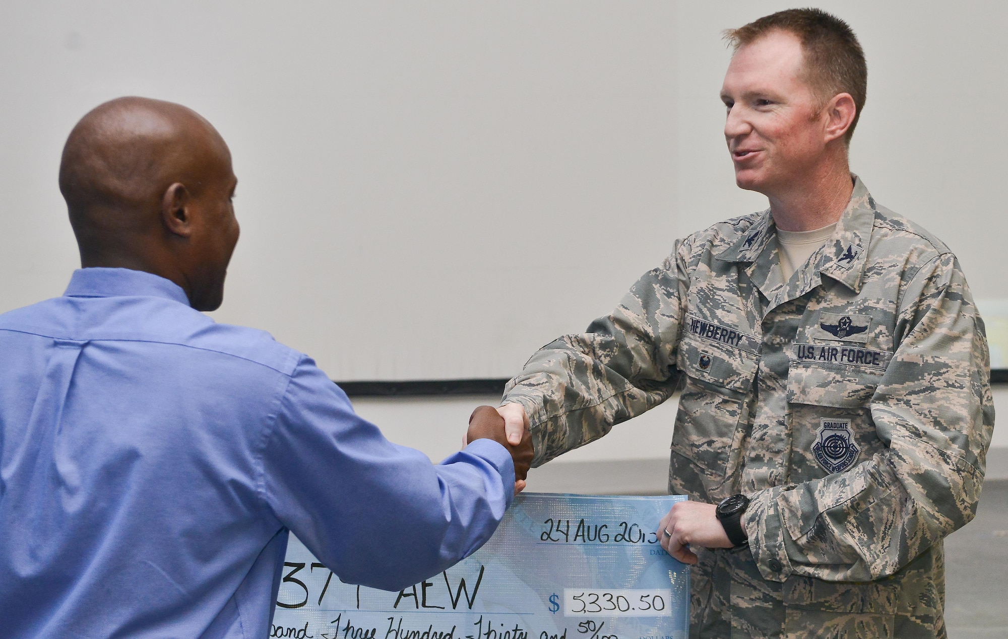 Chidley Lafontant, Combined Federal Campaign-Overseas manager, presents a check from 2014 CFC-O undesignated funds to Col. Stuart Newberry, 379th Air Expeditionary Wing vice commander, who received it on behalf of the 379th AEW August 27, 2015 at Al Udeid Air Base, Qatar. CFC gives military members the opportunity to contribute through donations for various charities. The campaign will begin September 21st and conclude November 21st. (U.S. Air Force photo/Staff Sgt. Alexandre Montes)
