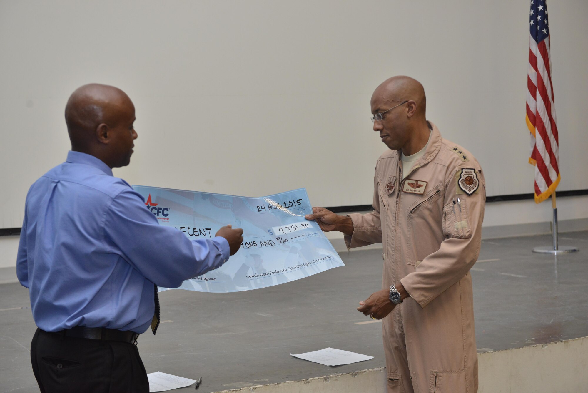 Chidley Lafontant, Combined Federal Campaign-Overseas manager, presents a check from 2014 CFC-O undesignated funds to Lt. Gen. CQ Brown Jr., U.S. Air Forces Central Command commander, who received it on behalf of AFCENT August 27, 2015 at Al Udeid Air Base, Qatar. CFC gives military members the opportunity to contribute through donations for various charities. The campaign will begin September 21st and run through November 21st. (U.S. Air Force photo/Staff Sgt. Alexandre Montes)