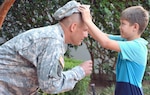 Kaleb Killian (right), presents his father, Col. Jerrod Killian, his headgear with his new rank during a promotion ceremony held at the U.S. Army Medical Department Museum courtyard on Fort Sam Houston Aug 4. Following the promotion ceremony, Killian relinquished command of the 264th Medical Battalion, 32nd Medical Brigade, U.S. Army Medical Department Center and School, U.S. Army Health Readiness Center of Excellence, during a change of command ceremony at the AMEDD Museum Amphitheater.