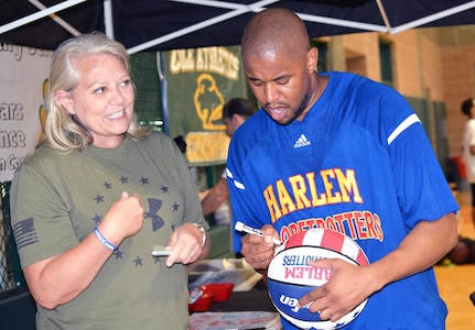 Harlem Globetrotters Shane “Scooter” Christensen autographs a ball for Simone Larson during a basketball camp held at Cole High School on JBSA-Fort Sam Houston Aug. 19.