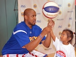 Harlem Globetrotters Shane “Scooter” Christensen teaches 4-year-old Roxanne Ajel how to balance a spinning basketball on her forefinger Aug. 19.