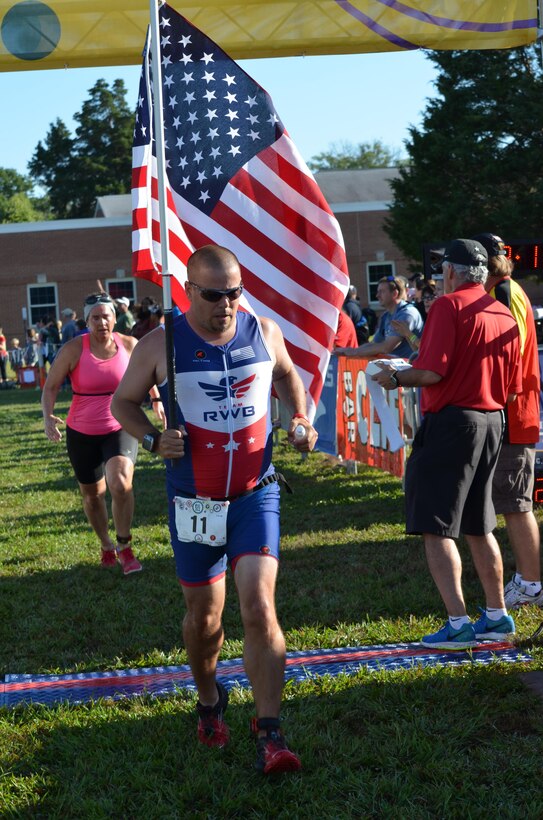 Robert Davies of Fredericksburg, Va., member of Team RWB, an athletic organization for veterans, completes the 5k run portion of Saturday’s Quantico Triathlon while carrying the American flag. Davies carried the flag for the entire run.