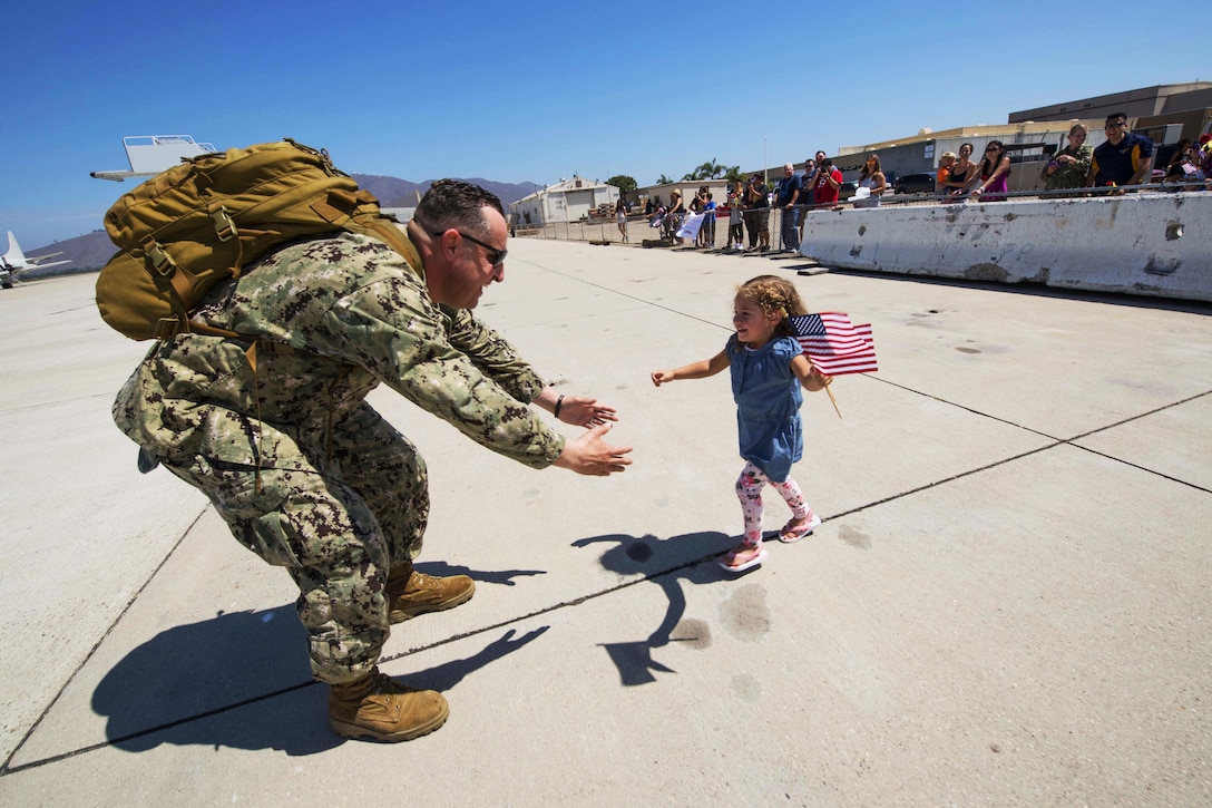 U.S. Navy Petty Officer 2nd Class Brandin Salazar greets his daughter on the flightline on Naval Base Ventura County following his return from deployment on Naval Base Ventura County, Calif., Aug. 26, 2015.  Salazar is a steelworker assigned to Naval Mobile Construction Battalion 5, which conducted maintenance and infrastructure improvements at U.S. military facilities in the U.S. Pacific Command area of operations. U.S. Navy photo by Chief Lowell Whitman