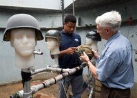 Dante Dobbins, a 2015 summer volunteer at Naval Surface Warfare Center, Carderock Division (NSWCCD) in West Bethesda, Md., helps Philip Dudt, a researcher at NSWCCD, test different applications of an explosive resistant coating on helmets, Aug. 8, 2015. According to Office of Naval Research (ONR) scientist, Dr. Roshdy Baroum, early research sponsored by ONR, identified that a coating of explosive resistant coating polymers could mitigate blast exposure to the brain. NSWCCD has been engaged with a major helmet manufacturer to produce such a helmet and final blast testing will be commenced shortly. The coating is also just being explored for use in football helmets and may a wide application in this arena as well if research goes forward. (U.S. Navy photo by Devin Pisner/Released)