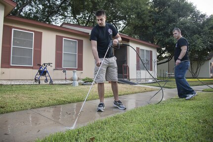 1st Lt. Benjamin Baumann (left), 435th Fighter Training Squadron student, and 1st  Lt. Colton Buechel, 435th FTS student, use a power washer to clean a walkway during a community service project August 14, 2015 at the Schertz Housing Authority in Schertz, Texas.  The project was a partnership effort between Joint Base San Antonio-Randolph and the city of Schertz to clean up the Veteran’s Memorial Plaza, Schertz Housing Authority and to serve a meal to the seniors at the Schertz Senior Center. (U.S. Air Force photo by Master Sgt. Sean M. Worrell/Released)