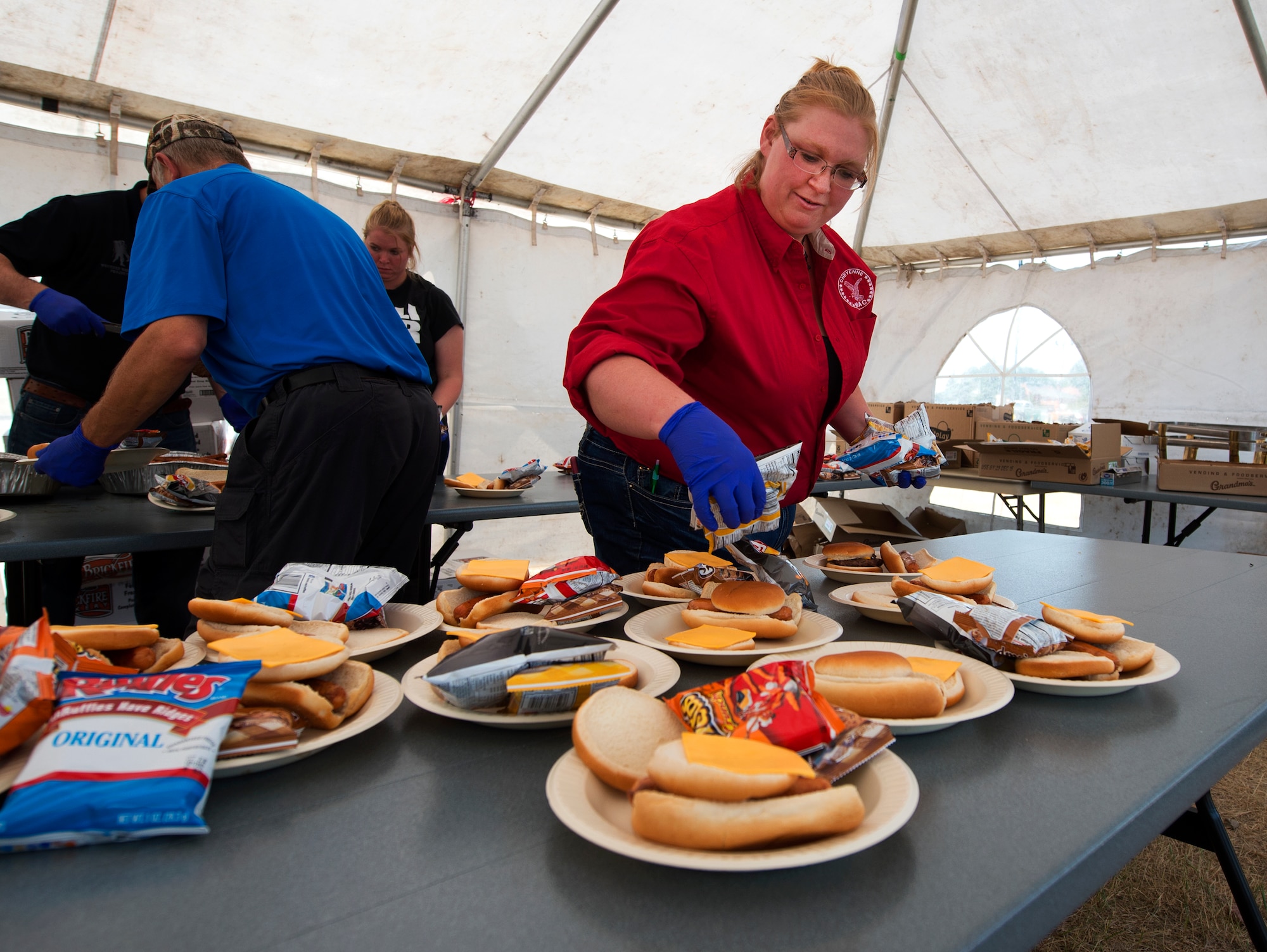 Christie Herron, a volunteer from the Chamber of Commerce's Military Affairs Committee, prepare plates of burgers, hot dogs and chips for the 90th Missile Wing Airmen, and their families, taking part in the annual Frontiercade on F.E. Warren Air Force Base, Wyo., Aug. 21, 2015. Frontiercade is meant to give F.E. Warren Airmen and their families a day of games, sports and free food before the start of the new school year. (U.S. Air Force photos by R.J. Oriez/Released)