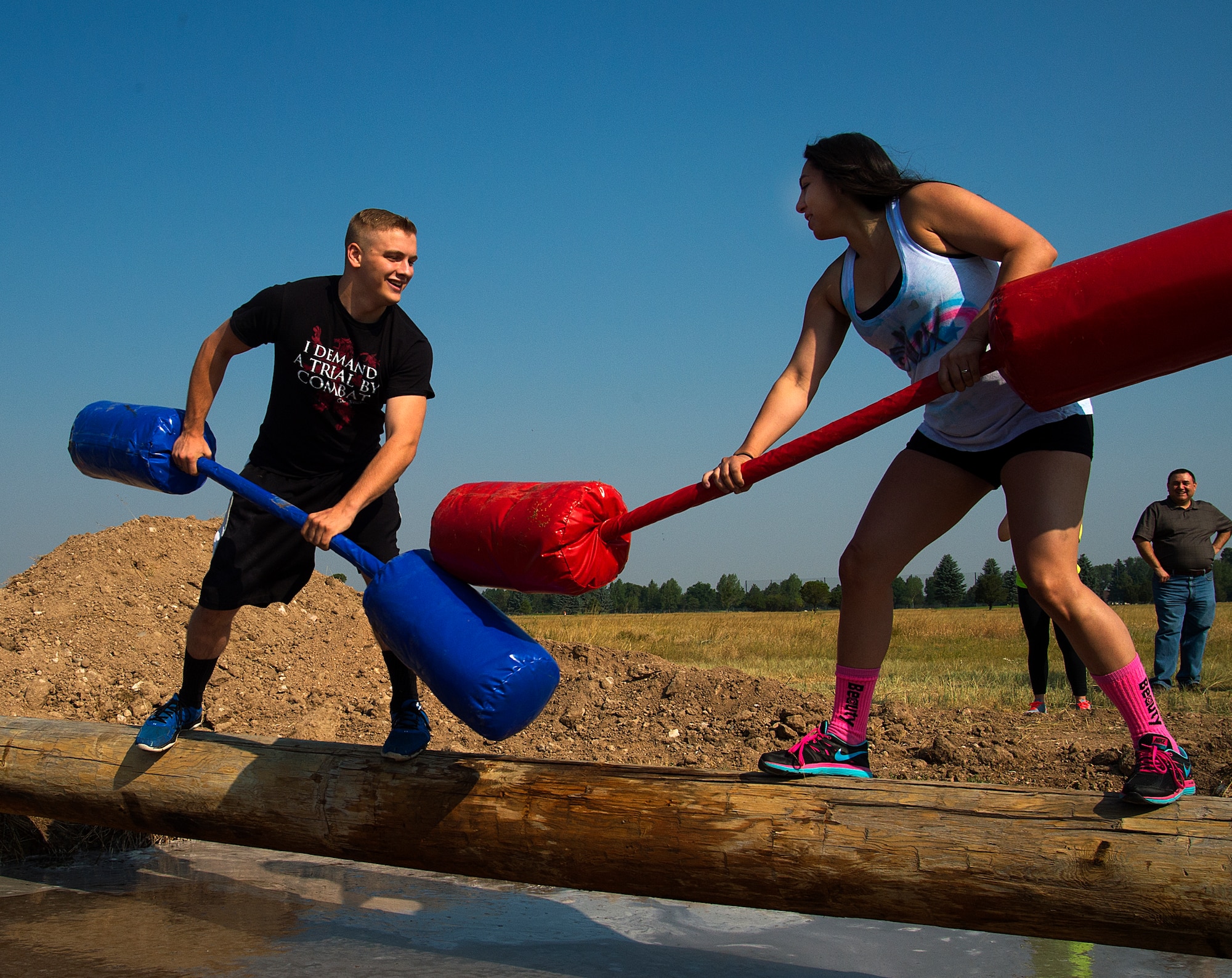Landon Strand, 90th Medical Group, and Alexandra Ayub, 90th Force Support Squadron,  face off with pugil sticks over muddy water on F.E. Warren Air Force Base, Wyo., as they take part in a jousting competition  Aug. 21, 2015. The two were taking part in Frontiercade, which is meant to give F.E. Warren Airmen and their families a day of games, sports and free food before the start of the new school year. (U.S. Air Force photos by R.J. Oriez/Released)