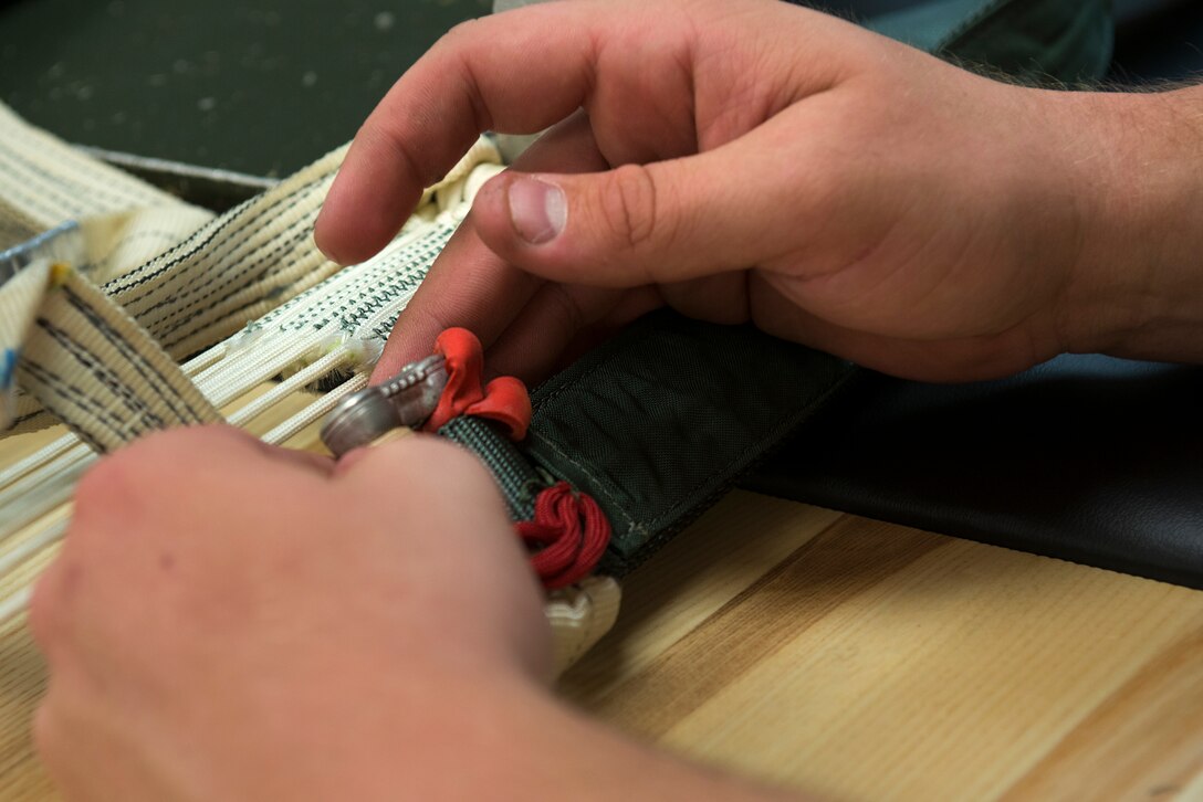A 23d Operations Support Squadron aircrew flight equipment journeyman inspects the connector links on a parachute Aug. 19, 2015, at Moody Air Force Base, Ga. The parachute packing process can take up to six hours to pack, inspect and repack, depending on the experience of the AFE member. (U.S. Air Force photo by Airman 1st Class Kathleen D. Bryant/Released)
