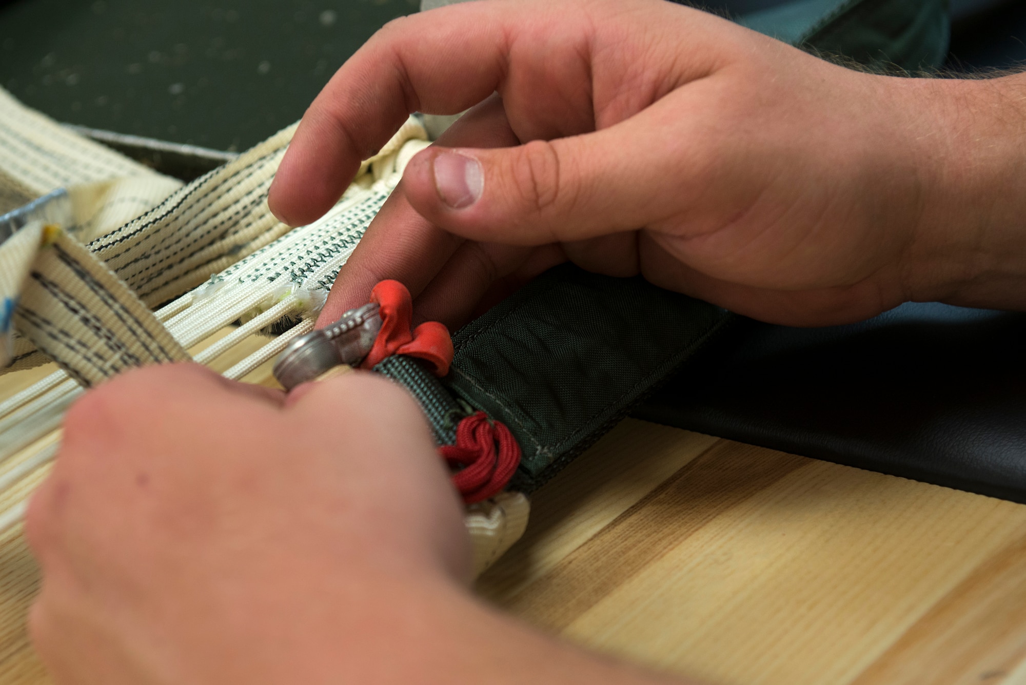 A 23d Operations Support Squadron aircrew flight equipment journeyman inspects the connector links on a parachute Aug. 19, 2015, at Moody Air Force Base, Ga. The parachute packing process can take up to six hours to pack, inspect and repack, depending on the experience of the AFE member. (U.S. Air Force photo by Airman 1st Class Kathleen D. Bryant/Released)
