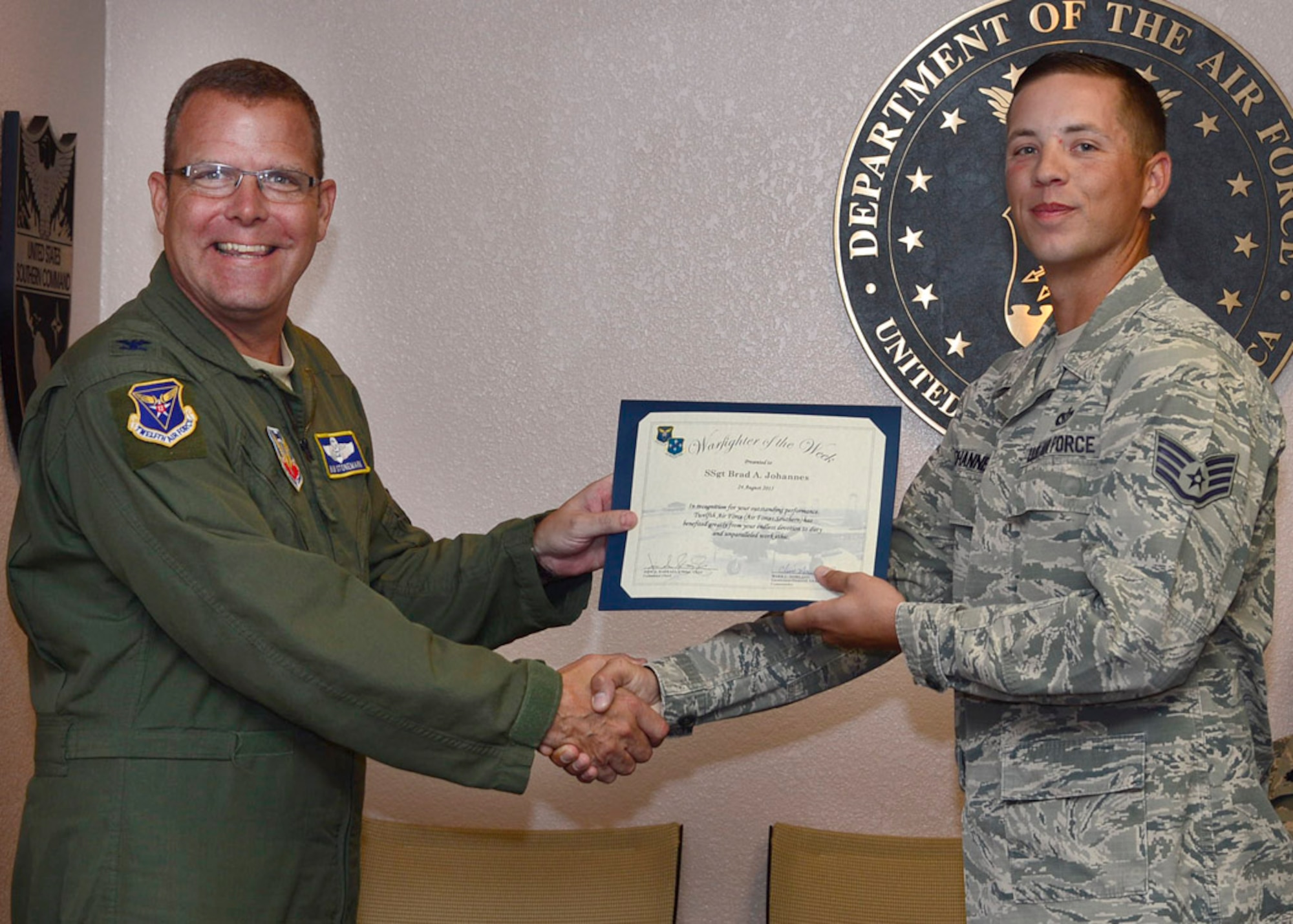 Col. Robert Stonemark, 12th Air Force (Air Forces Southern) chief of staff, presents Staff Sgt. Brad Johannes, 12th AF (AFSOUTH) manager of engineering operations, with the Warfighter of the Week certificate during a staff meeting at Davis-Monthan AFB, Ariz., Aug. 24, 2015. War Fighter of the Week is an opportunity for the Airmen who represent 12th AF (AFSOUTH) to share their own story. The Warfighter of the Week initiative aligns with the 12th AF (AFSOUTH) commander’s priority of creating a work environment where someone knows you both professionally and personally. (U.S. Air Force photo by Tech. Sgt. Heather Redman/Released)