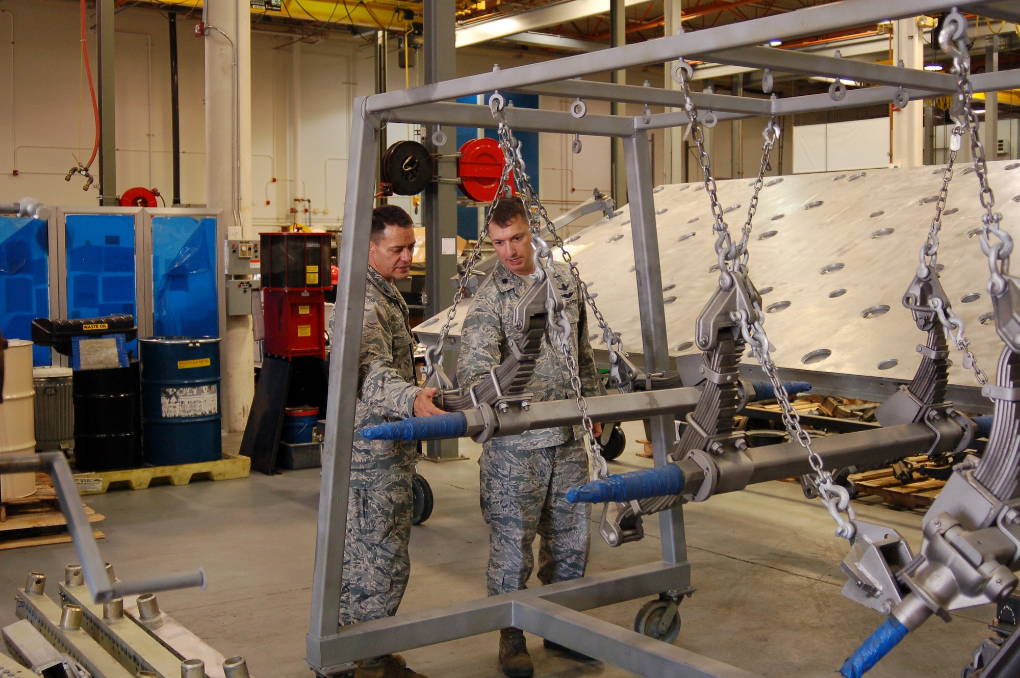 The axles of a MHU-110/M munitions trailer being overhauled by the 526 EMXS at Hill AFB are checked by Col. Jeffrey Gates, left, and Lt. Col. Jamey Sillence with the Air Force Life Cycle Management Center at Warner-Robins AFB. Their office provides the requirements and funding for the MHU-110 overhaul, as well as various other 526 EMXS workloads. The men were on base to check the progress of various repair lines the Ogden ALC supports for their programs. (Air Force photo)