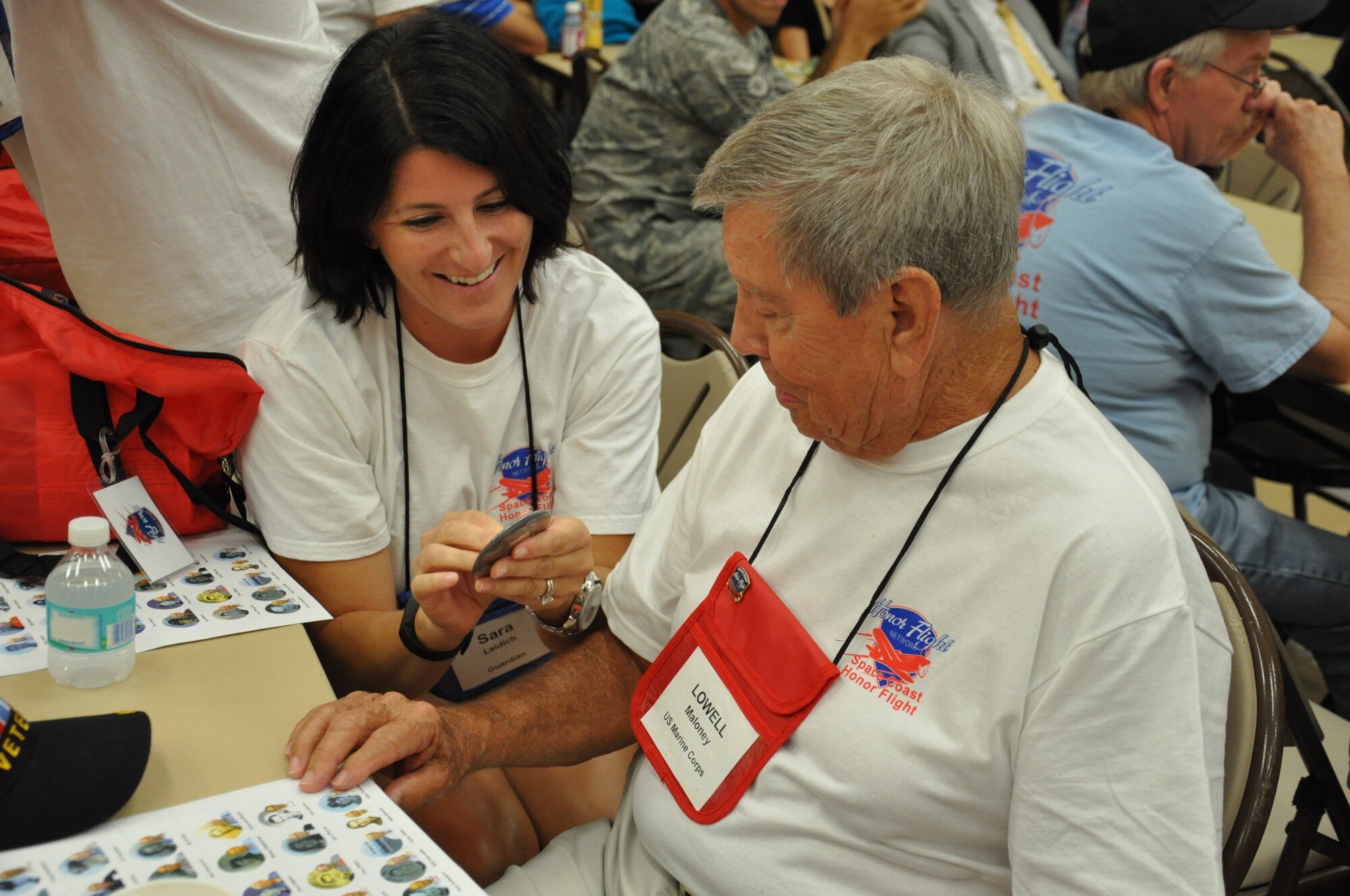 Sara Leidich, Honor Flight guardian and daughter of Lowell Maloney, right, pins a photo of Maloney from when he served in the U.S. Marine Corps during the Korean War at the Wickham Senior Center in Melbourne, Fla., Aug. 22, 2015. The Space Coast Honor Flight sent 21 World War II and four Korean War veterans to Washington, D.C., to visit their war memorials in Washington D.C. (U.S. Air Force photo by 1st Lt. Alicia Premo/Released)