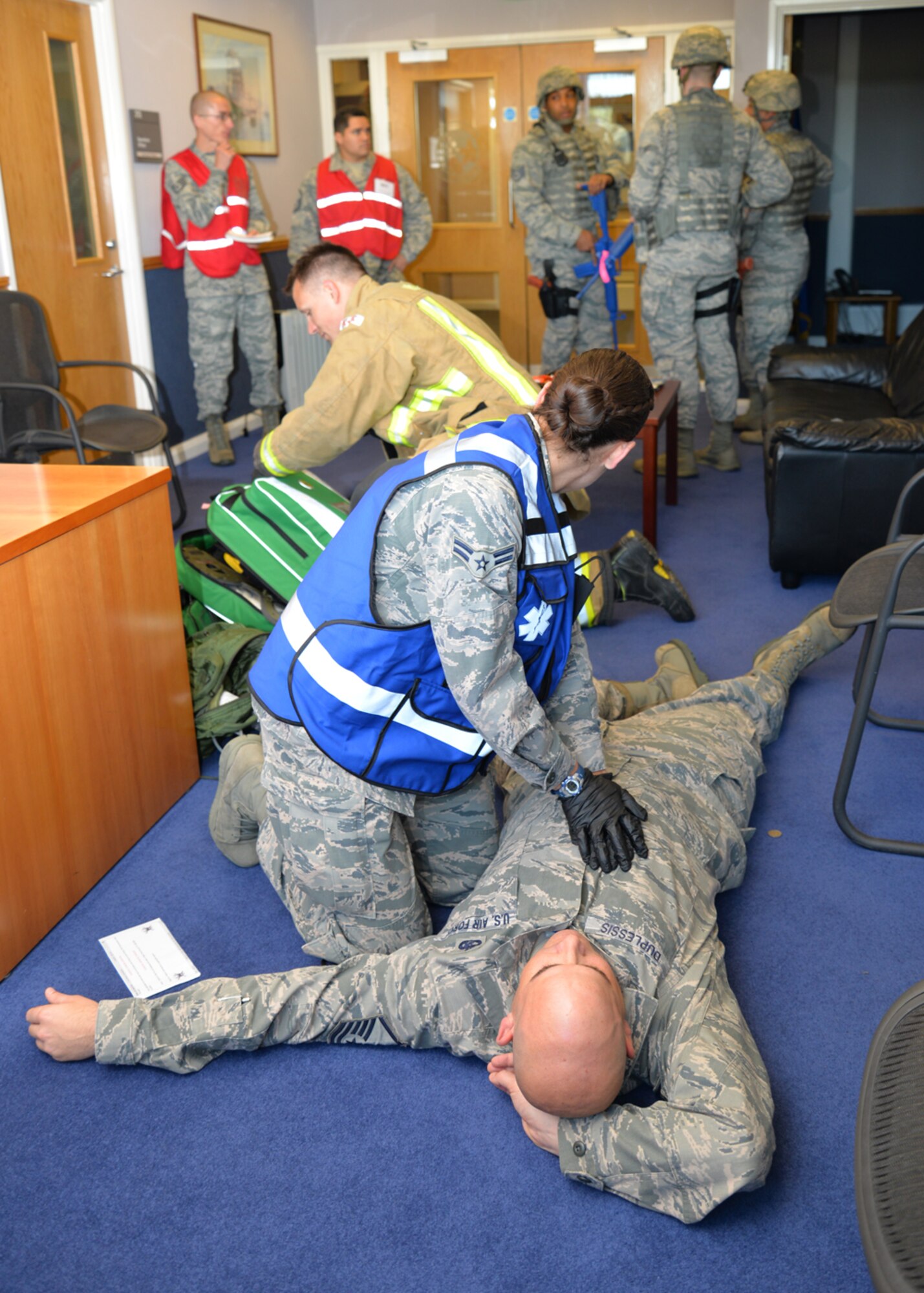 Airmen from the 100th Civil Engineer Squadron Fire Department and 48th Medical Group respond to a simulated victim during an active shooter exercise as 100th Air Refueling Wing inspection team members evaluate the situation Aug. 25, 2015, on RAF Mildenhall, England. As part of an emergency lockdown exercise, an armed assailant was on base testing service members’ reactions to the scenario. (U.S. Air Force photo by Karen Abeyasekere/Released)