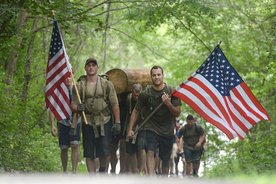 Staff Sgt. Lee Shortell, left, Patriot Honor Guard ceremonial guardsman, and Staff Sgt. Matthew Marquart, 66th Security Forces Squadron Combat Arms NCO in charge, carry the United States Flag as they lead Airmen as part of the Team Cohesion Challenge on base Aug. 24. The event was created to give Airmen an opportunity to participate in adventure-type events while incorporating the pillars of Comprehensive Airman Fitness at the same time. (U.S. Air Force photo by Jerry Saslav)