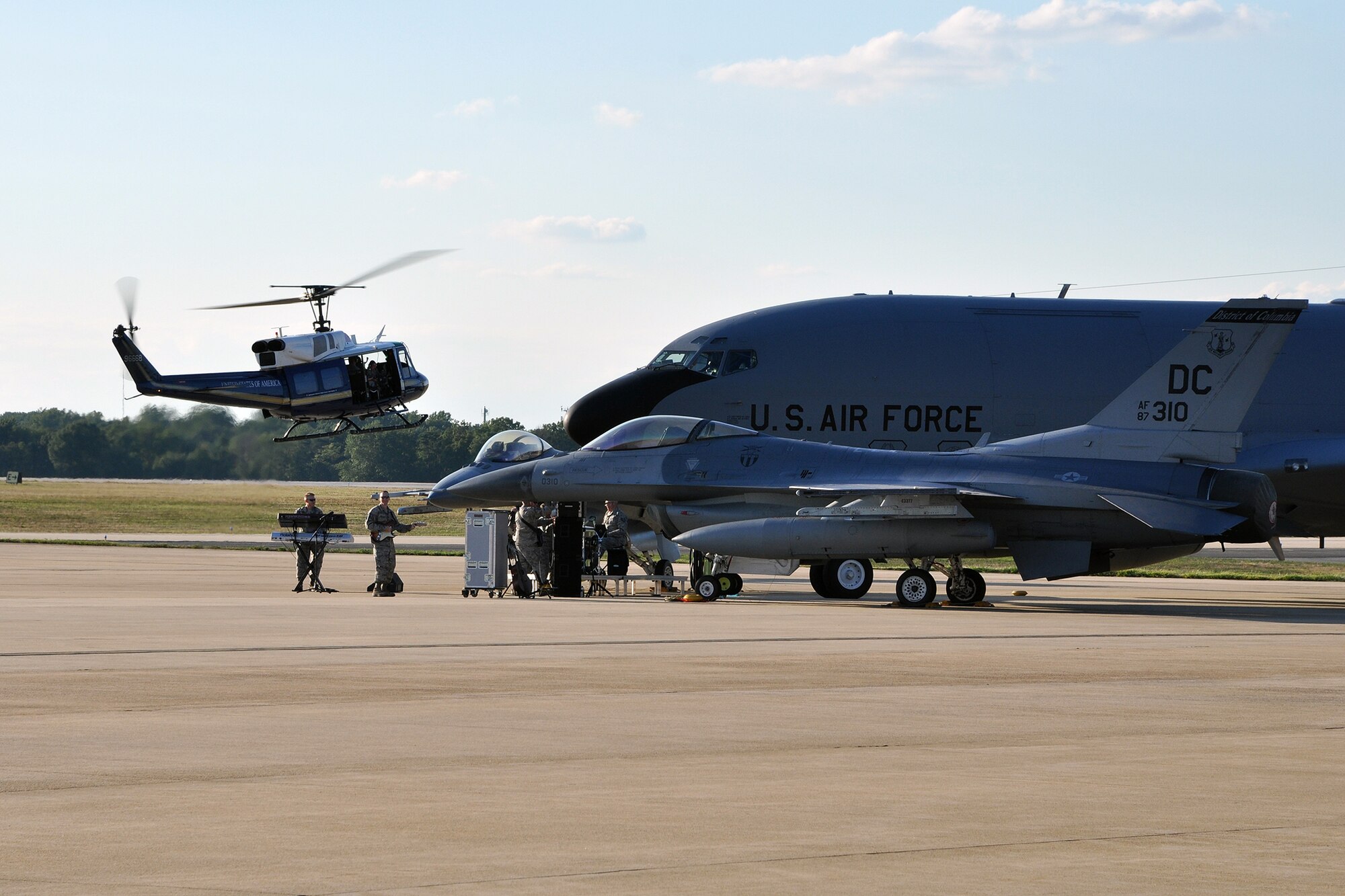 A 1st Helicopter Squadron UH-1N Huey performs a flyby of a production set to capture aerial videography of an up-and-coming music video for the U.S. Air Force band Max Impact on the Joint Base Andrews flightline Aug. 26, 2015. A 459th Air Refueling Wing KC-135R Stratotanker and 113th Wing F-16 Fighting Falcon helped set the stage for the band during the media event. (U.S. Air Force photo/Kat Lynn Justen)